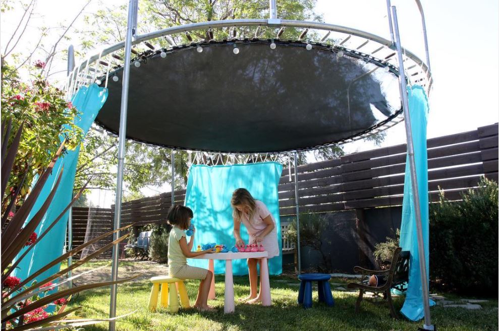 old trampoline repurposed into a play fort for children