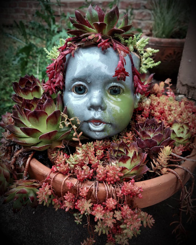 Painted doll head planters succulent arrangement.