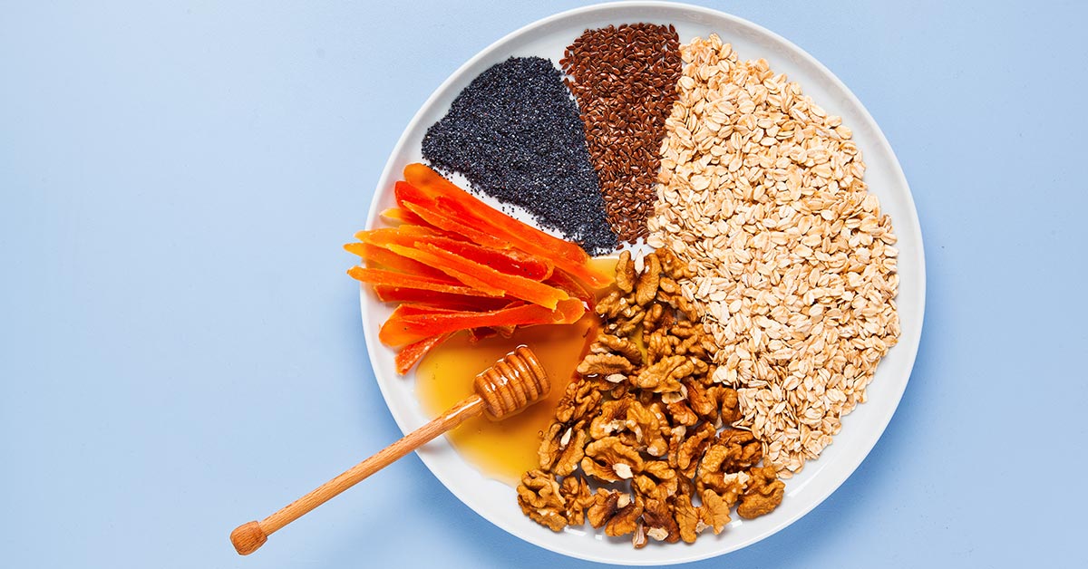 a plate of various foods made to look like a pie chart including honey, nuts, grains and seeds