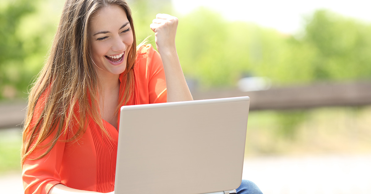 woman celebrating with clenched fist using laptop