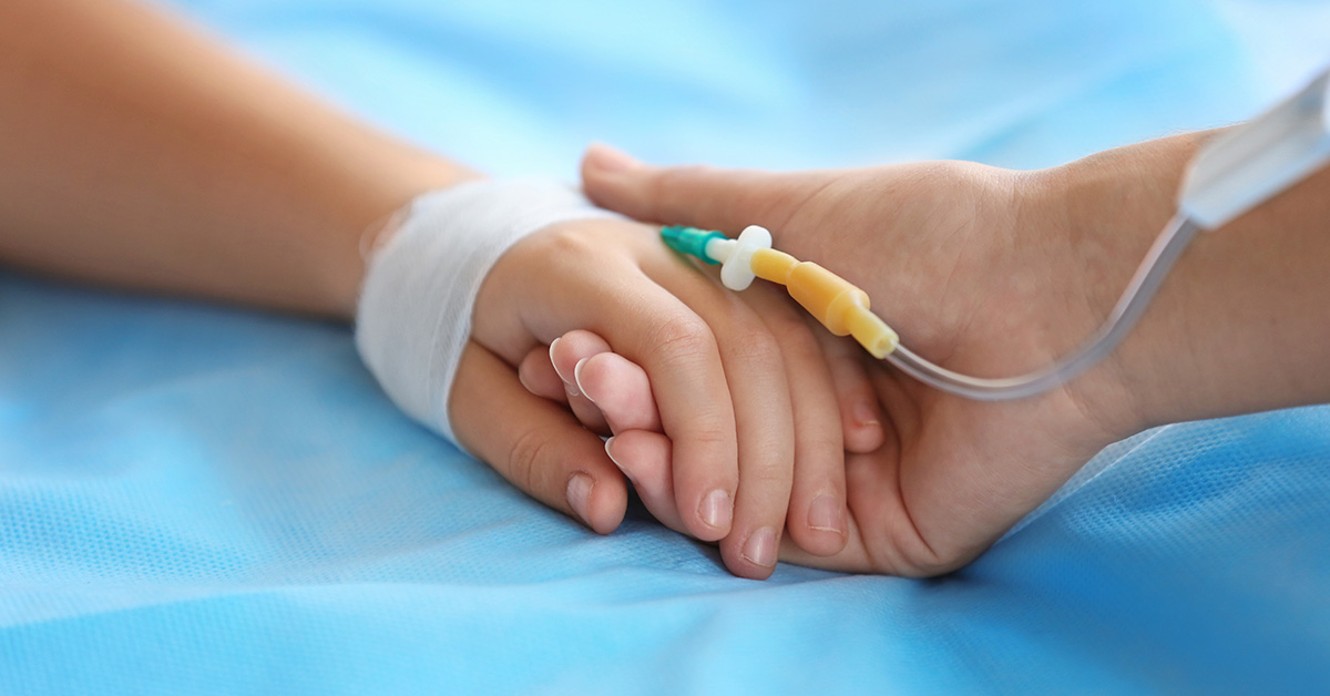 childs hand with IV inserted being held by a parent