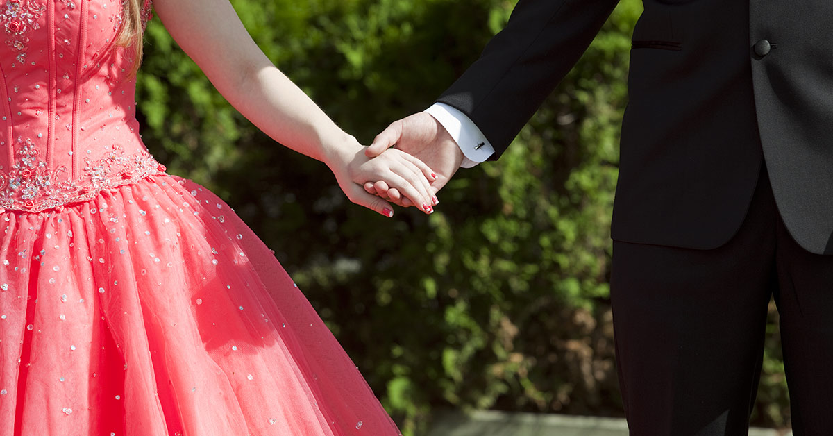 couple holding hands. Female dress in a prom dress (left) and make in Tuxedo (right)