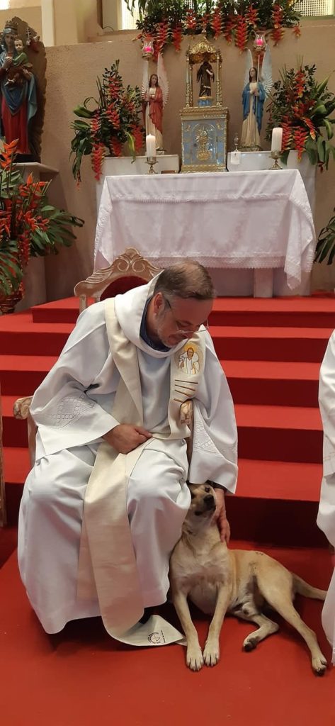 Father Gomes petting a rescue dog during service