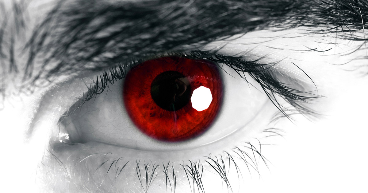 close up of an eye. The image is black and white, but the iris of the eye is red