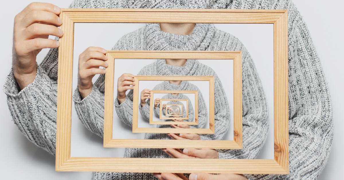 person holding a framed image of them self holding the same image of themself creating a mirror like effect